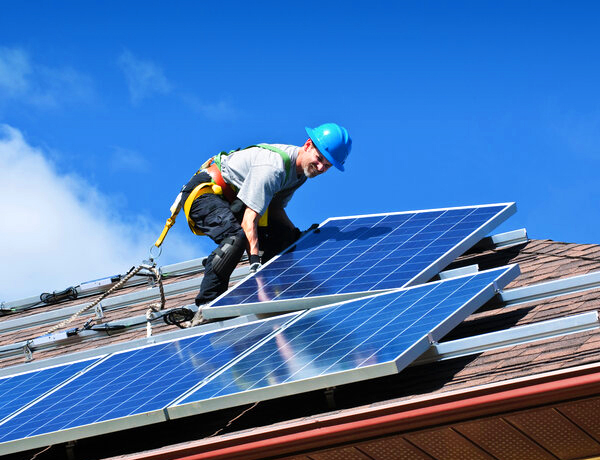 Monteur bei der Montage von Photovoltaikmodulen auf einem Hausdach