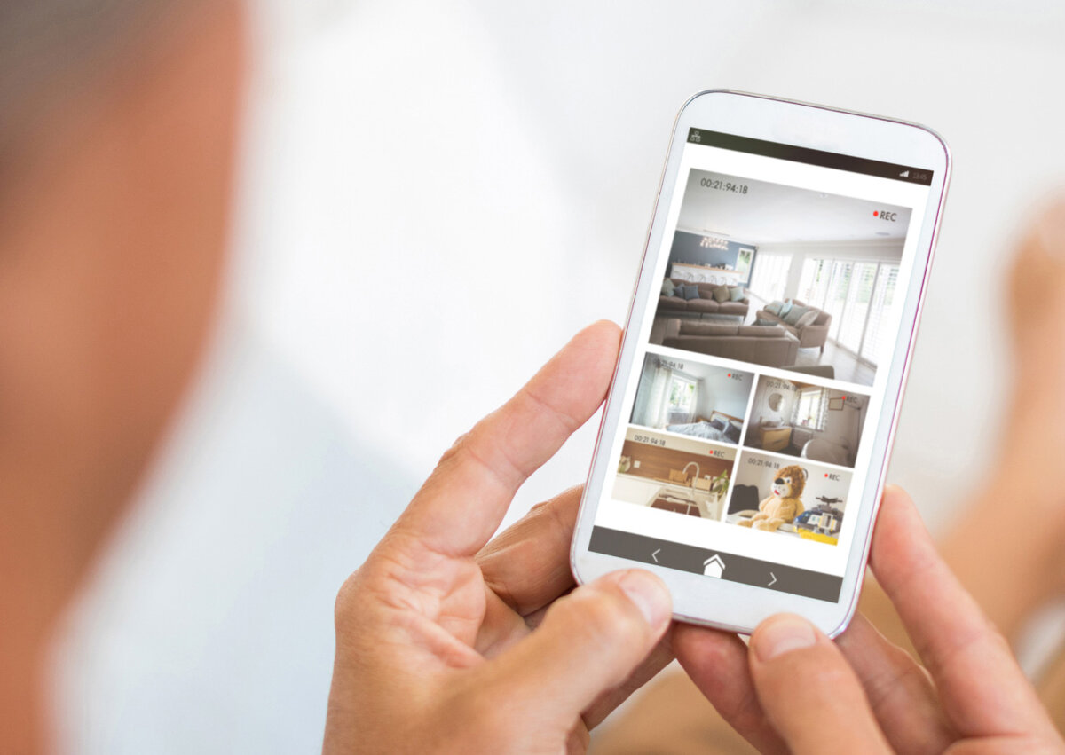 Person prüft die Live-Bilder einer installierten Kameraüberwachung auf einem Smartphone